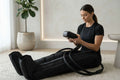 Woman using Elevate Performance Systems Flow Recovery Boots with air compression controller in a bright home setting.